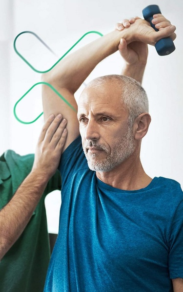 A close-up photograph featuring a trainer guiding a man during a dumbbell exercise, highlighting professional assistance in a fitness context.